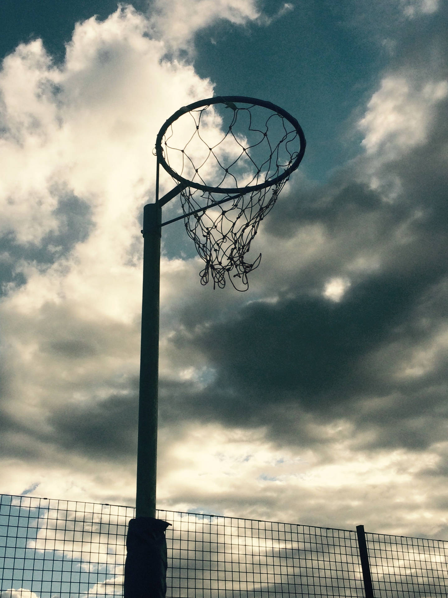 Victory At Her Fingertips – A Netball Player Aiming For The Hoop On An Outdoor Court