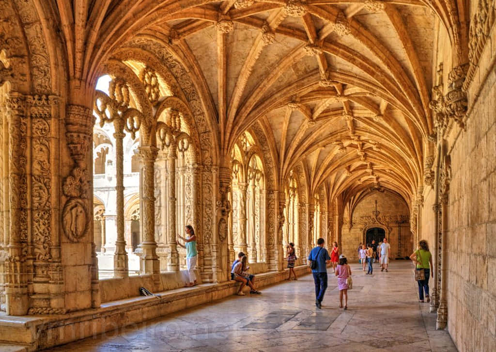 Visitors Exploring The Historic Mosteiro Dos Jeronimos In Lisbon, Portugal. Background