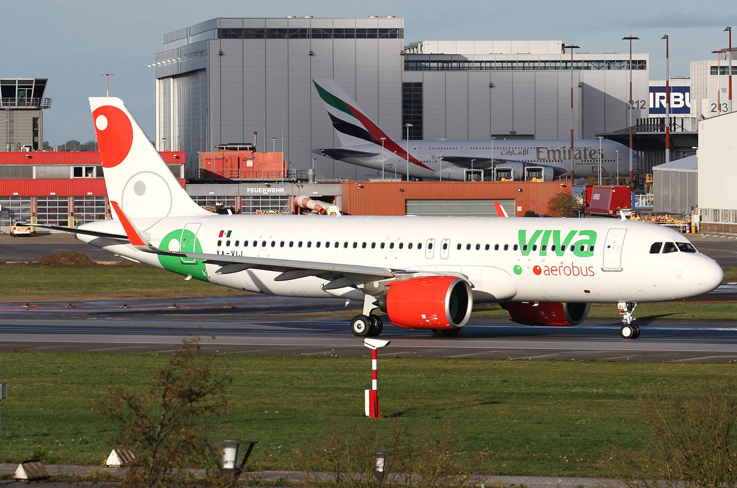 Viva Aerobus Airport With Grass And Buildings Background