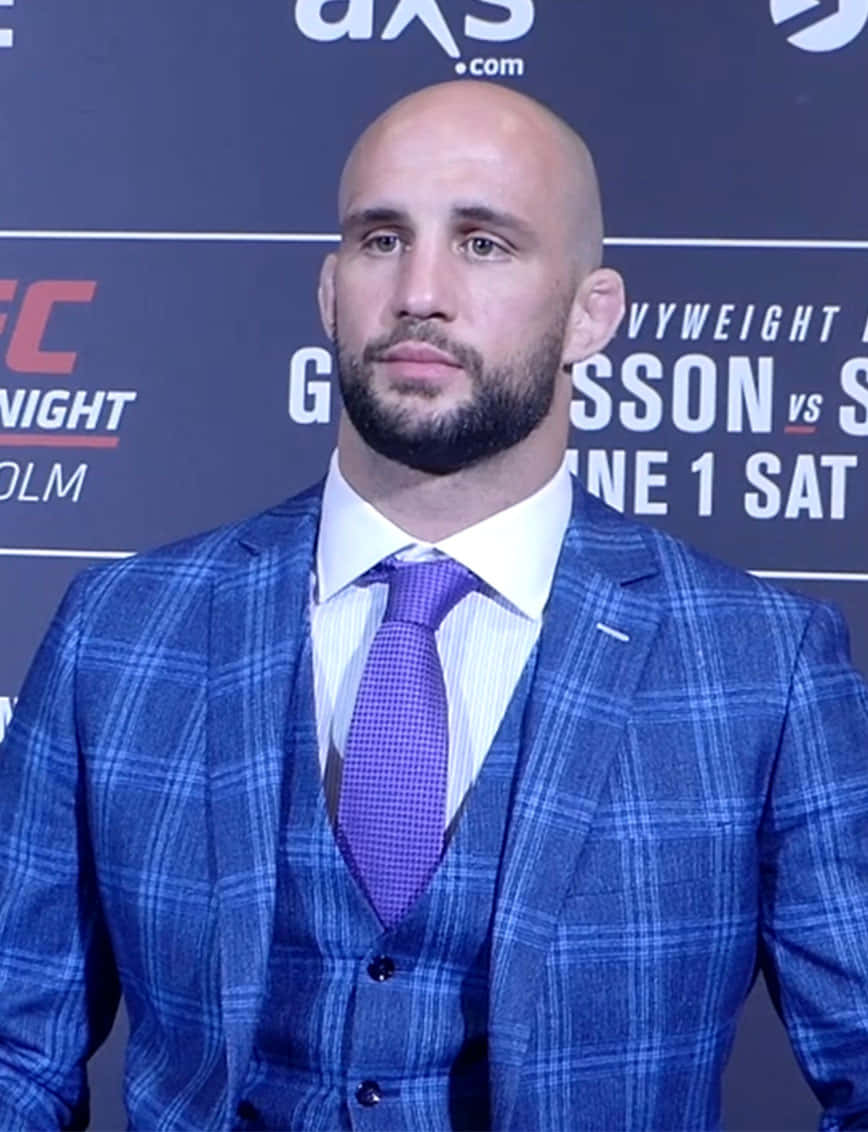 Volkan Oezdemir Posing In A Plaid Suit And Tie Background
