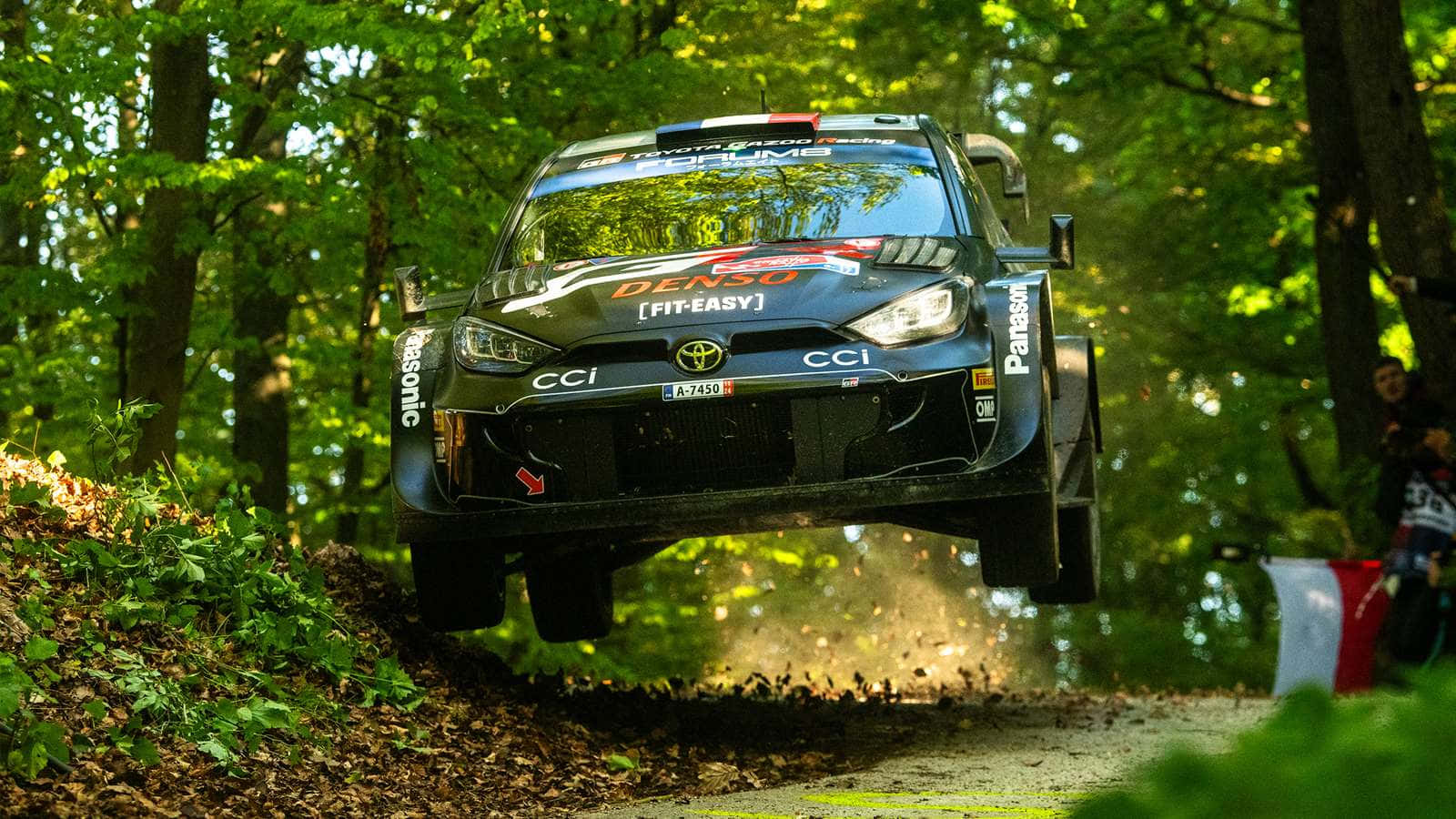W R C Rally Car Jumpingin Forest Stage Background