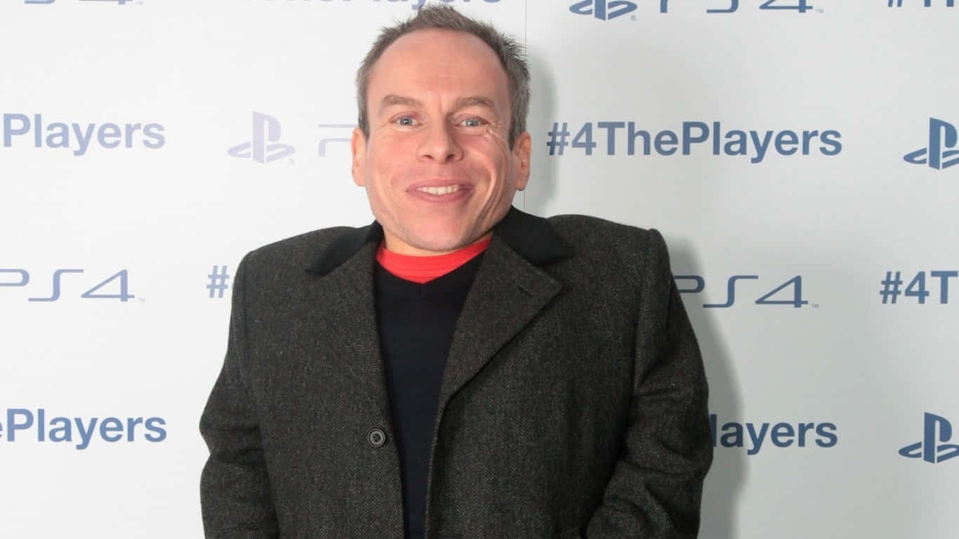 Warwick Davis Smiling At An Event Background