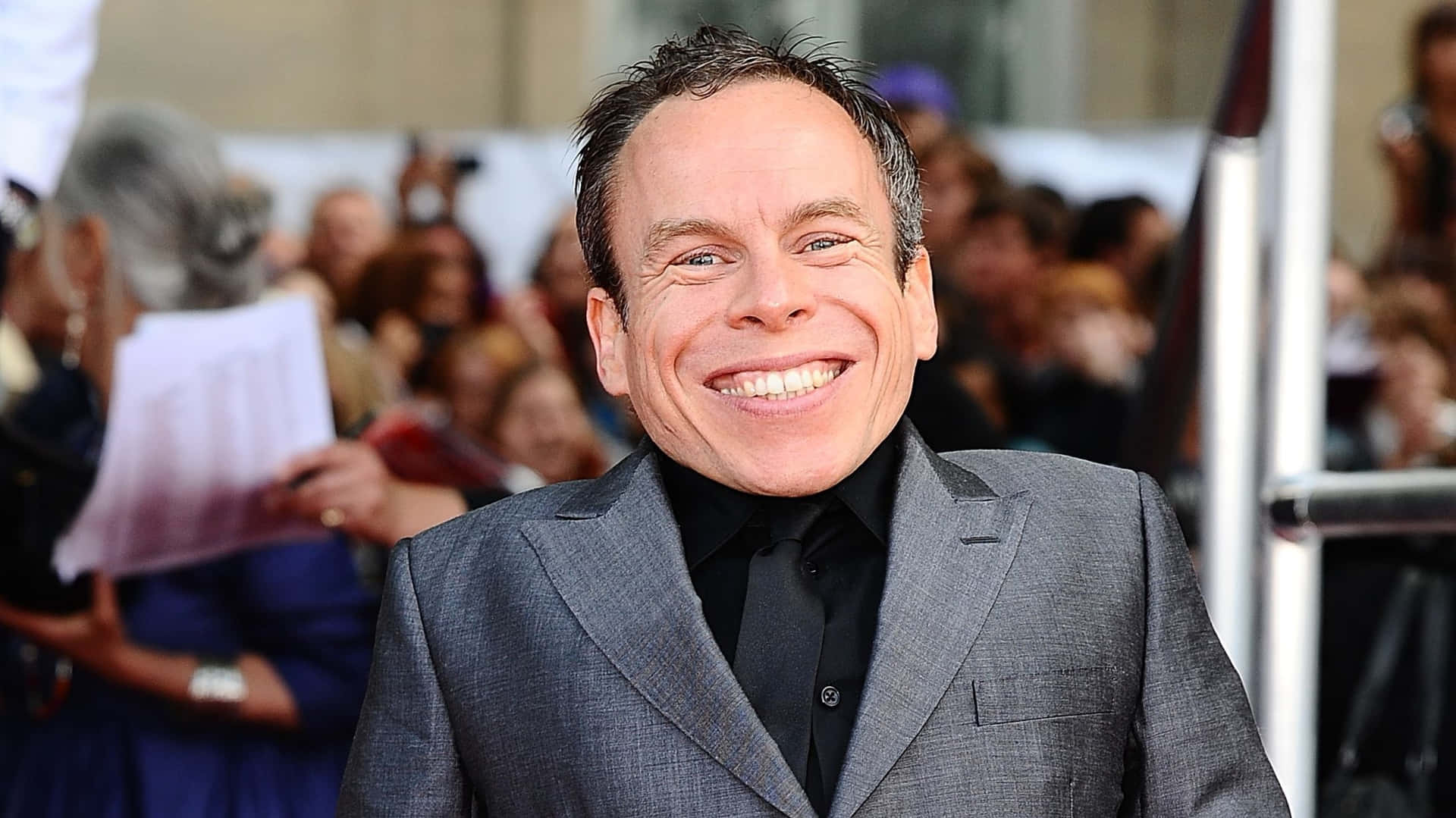 Warwick Davis Smiling In A Close-up Portrait Background