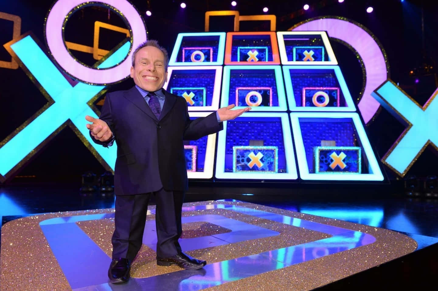 Warwick Davis Striking A Smiling Pose During An Event Background