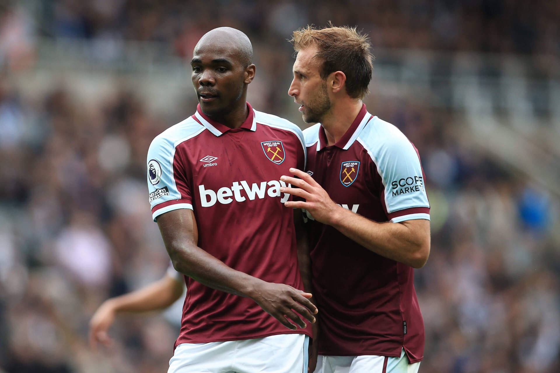 West Ham United Players Discussing Strategy During Match Background