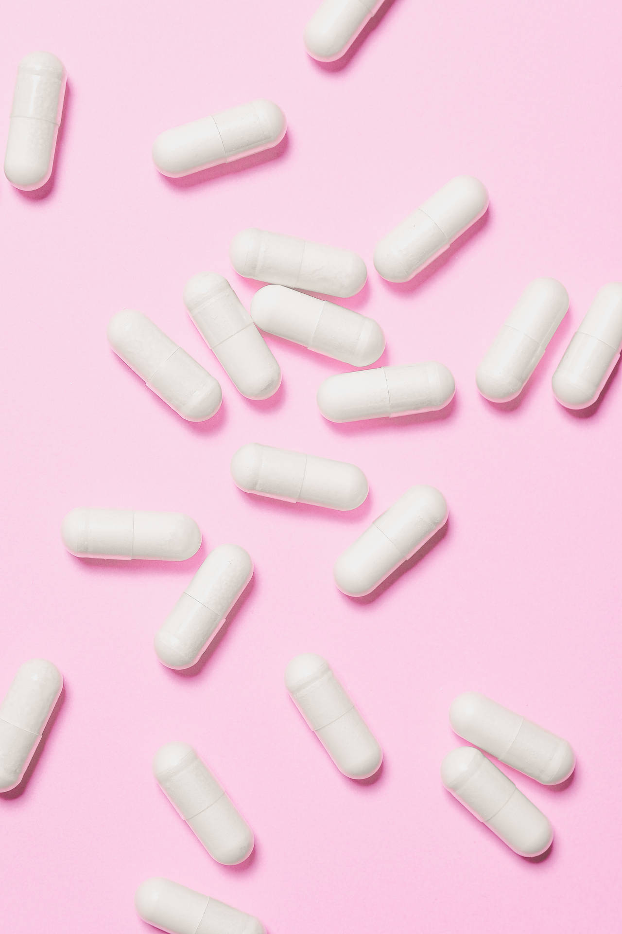 White Capsules On Pink Background