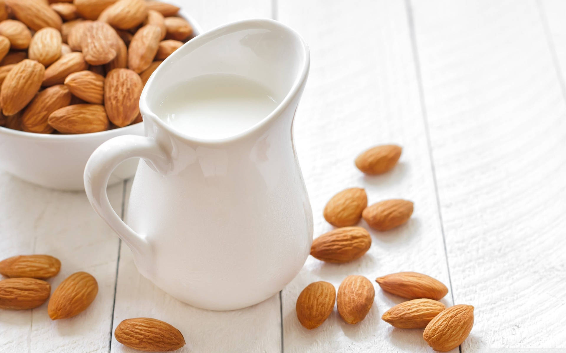 White Pitcher Of Almond Milk With Nuts Background