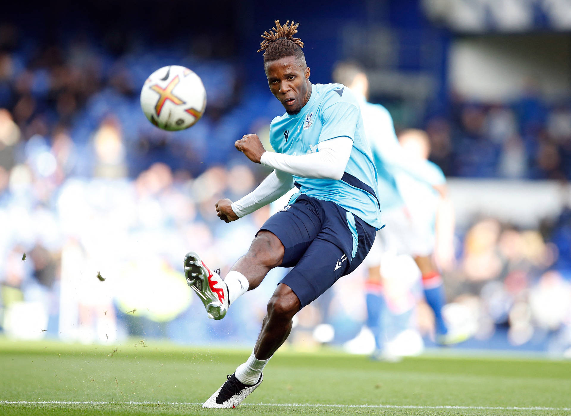 Wilfried Zaha Kicking Football On Field Background