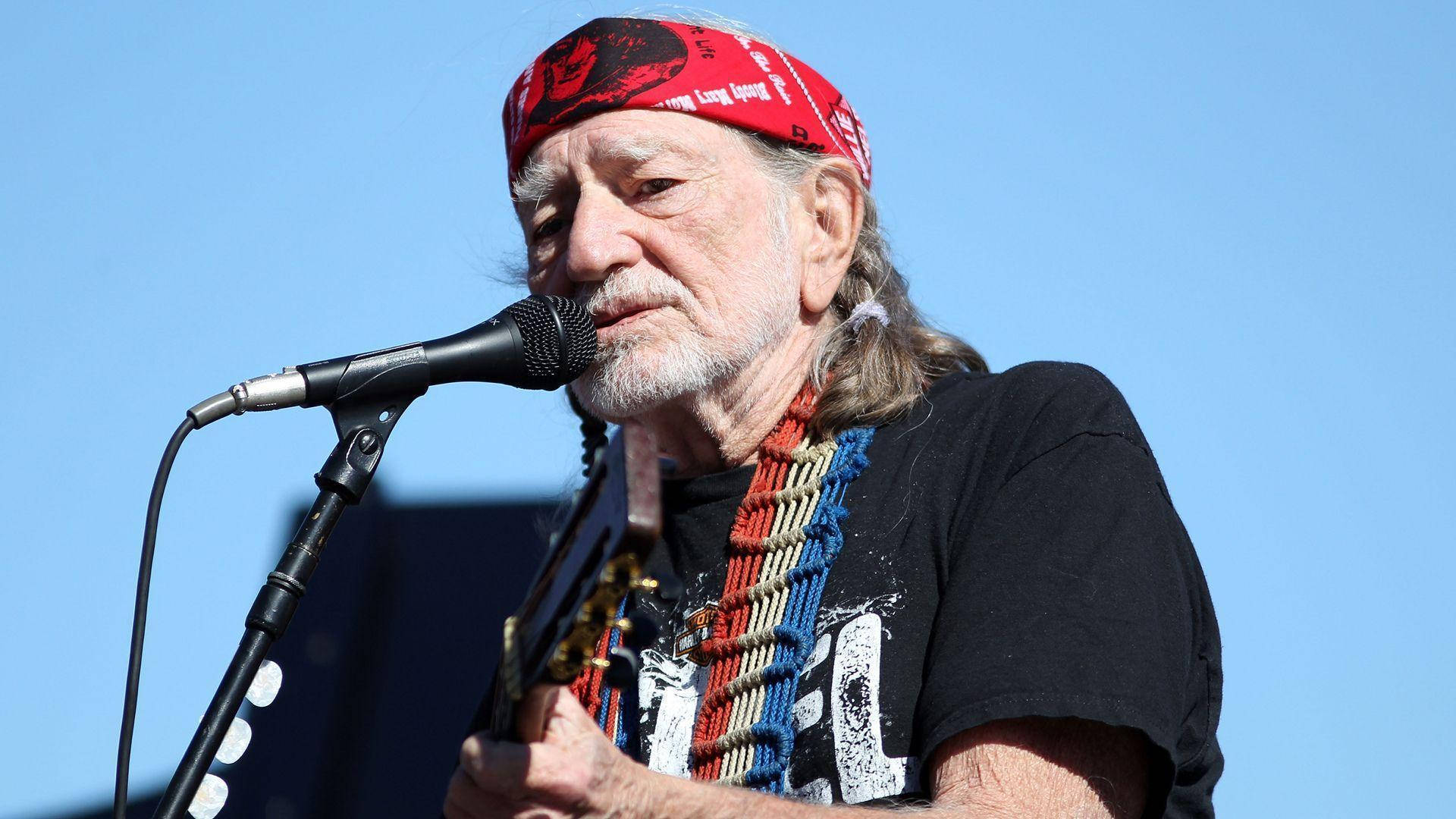 Willie Nelson Singing While Playing Guitar Background