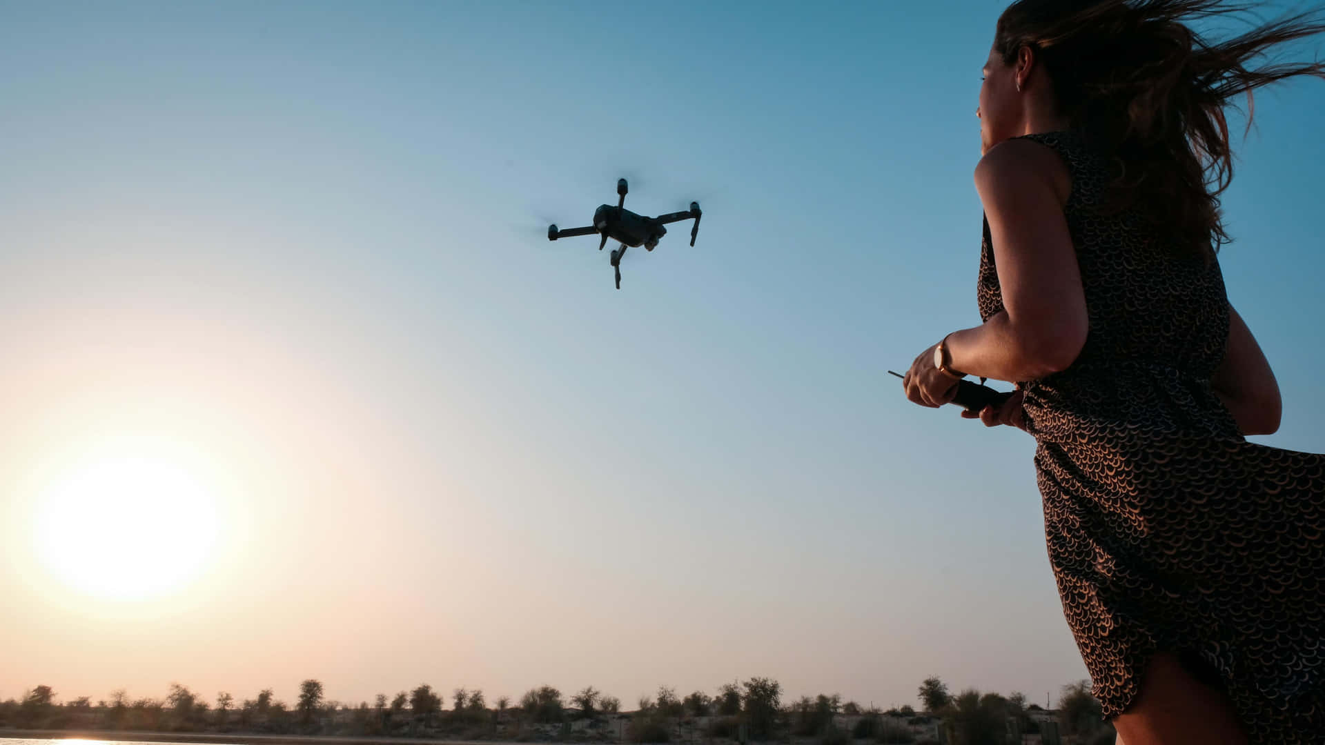 Woman Controlling Droneat Sunset