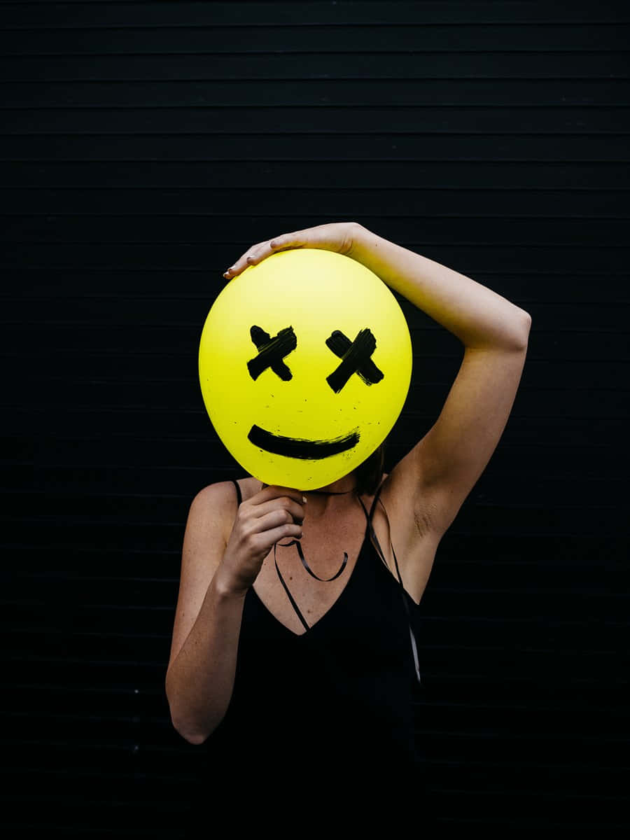 Woman Holding A Yellow Smiley Face Balloon Background