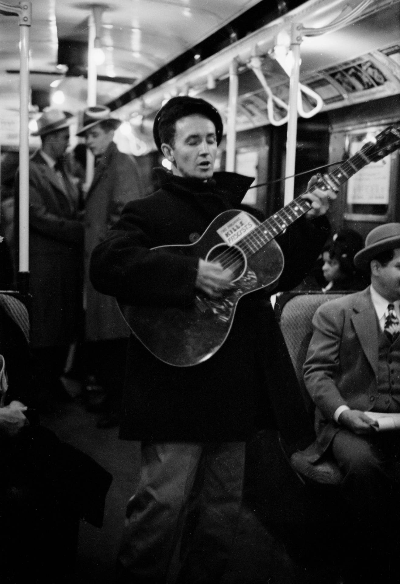 Woody Guthrie Playing Guitar In New York Subway Background