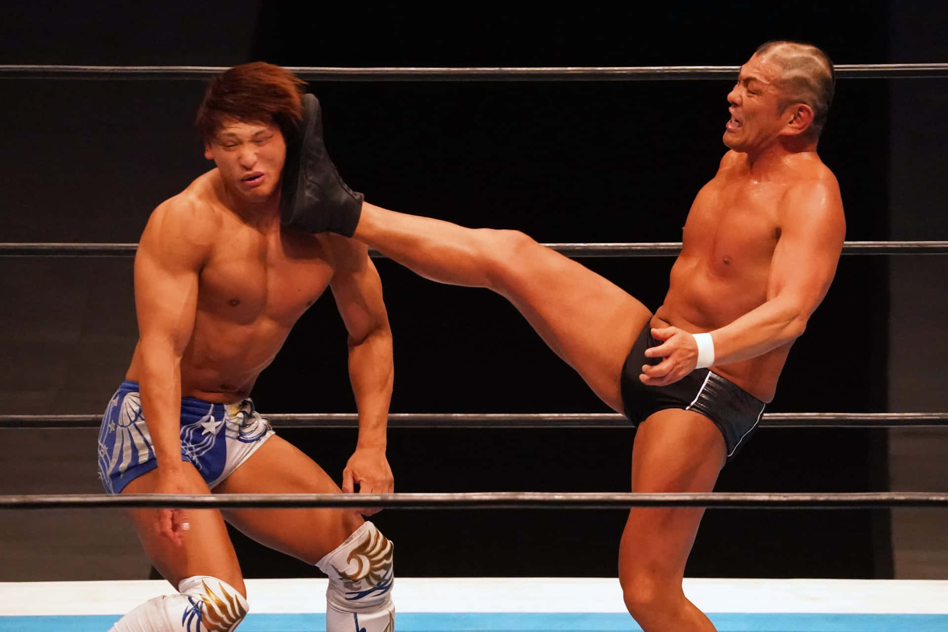 Wrestler Minoru Suzuki Lethal Kick On Kota Ibushi In The Ring Background