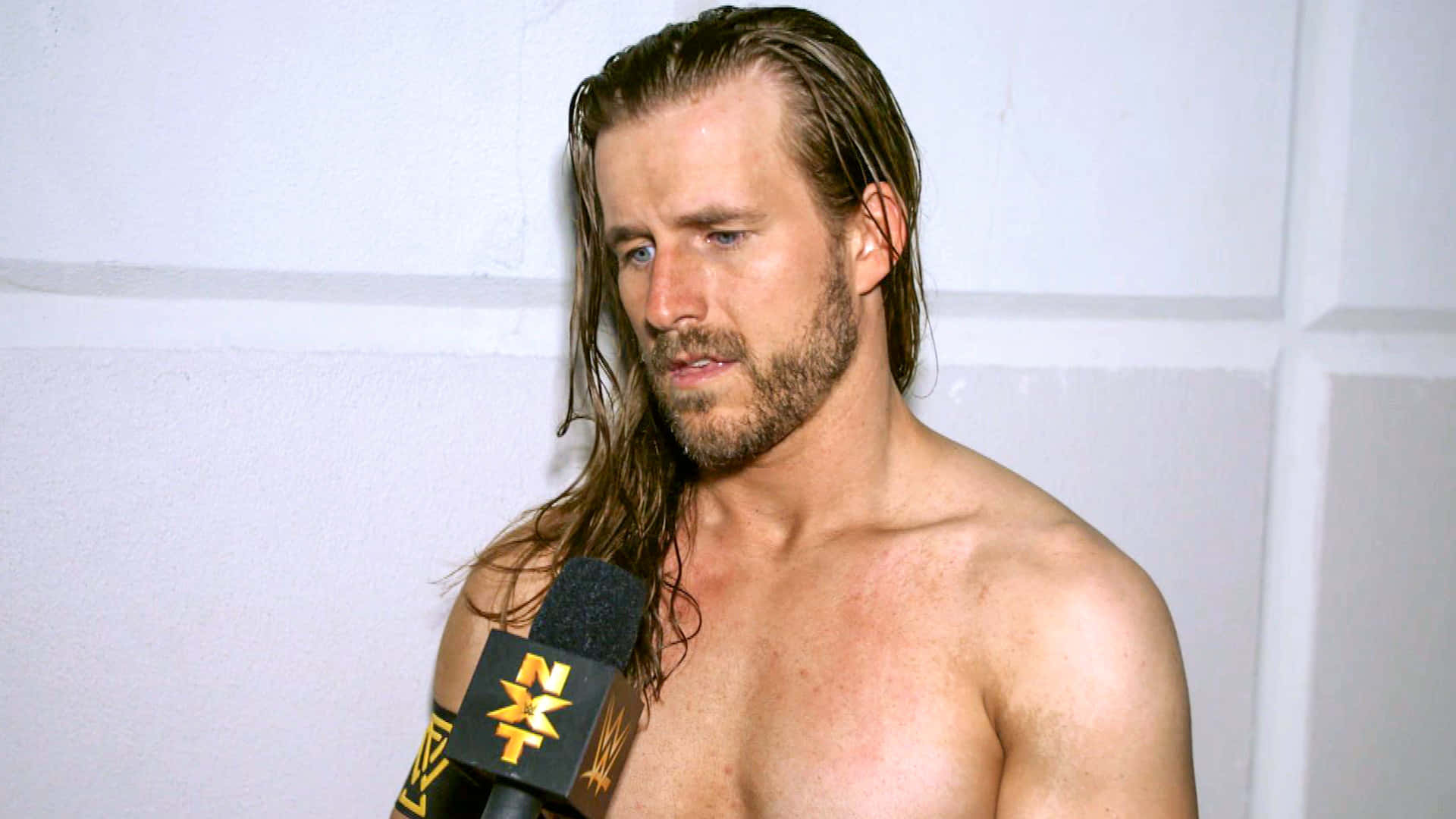 Wwe Superstar Adam Cole Engaging In A Backstage Interview. Background