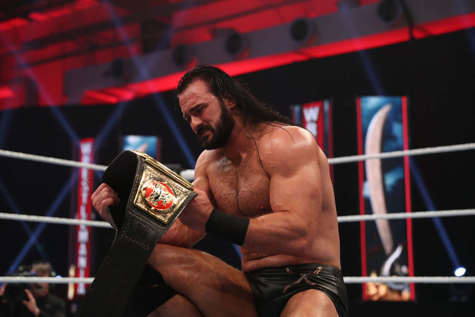 Wwe Superstar Drew Mcintyre Triumphantly Holding The Raw Championship Belt. Background