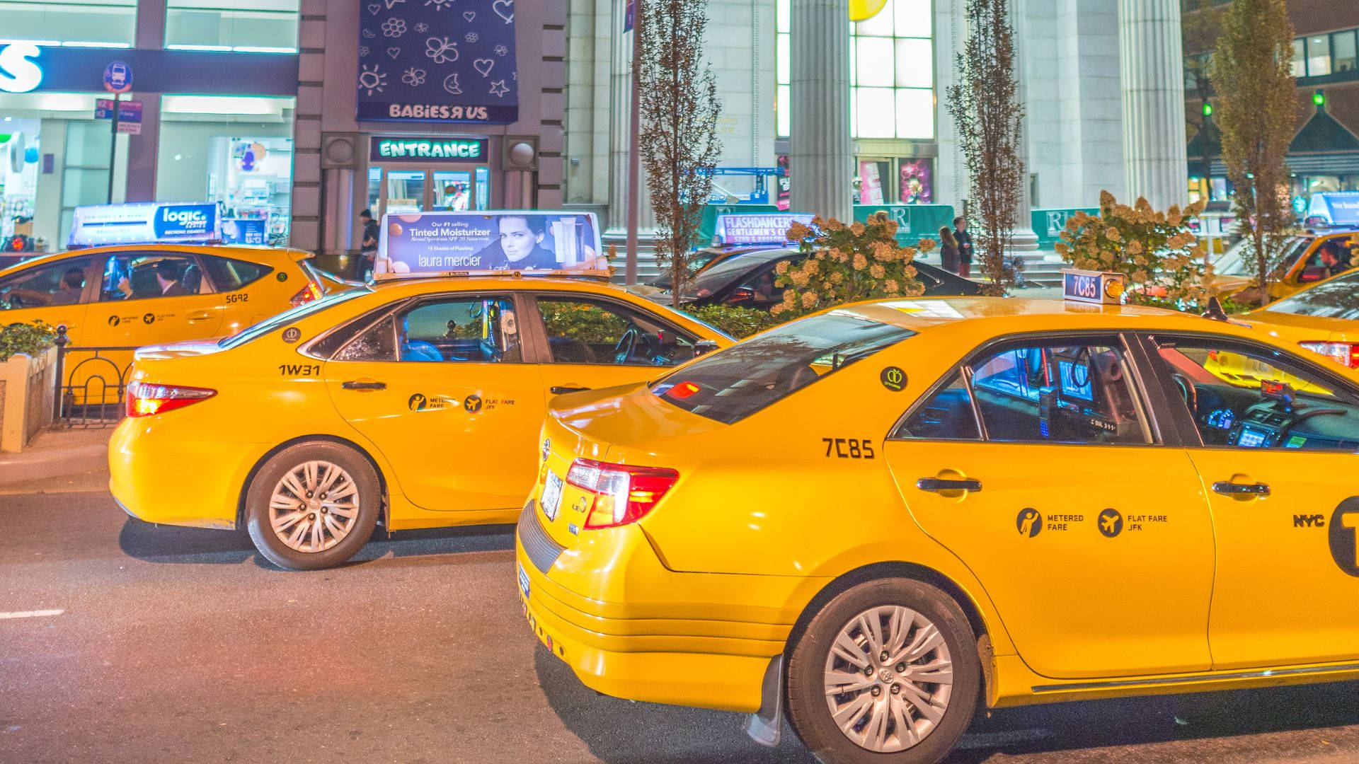Yellow Taxi Cab In Front Of Mall Background