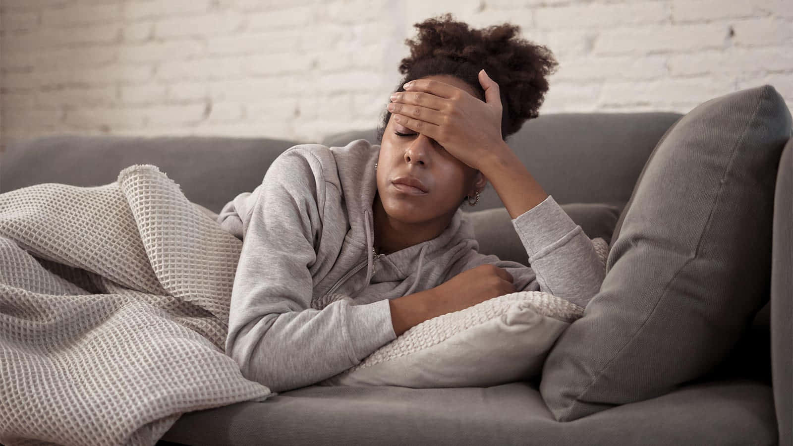 Young Black Woman With Fever On Couch Background