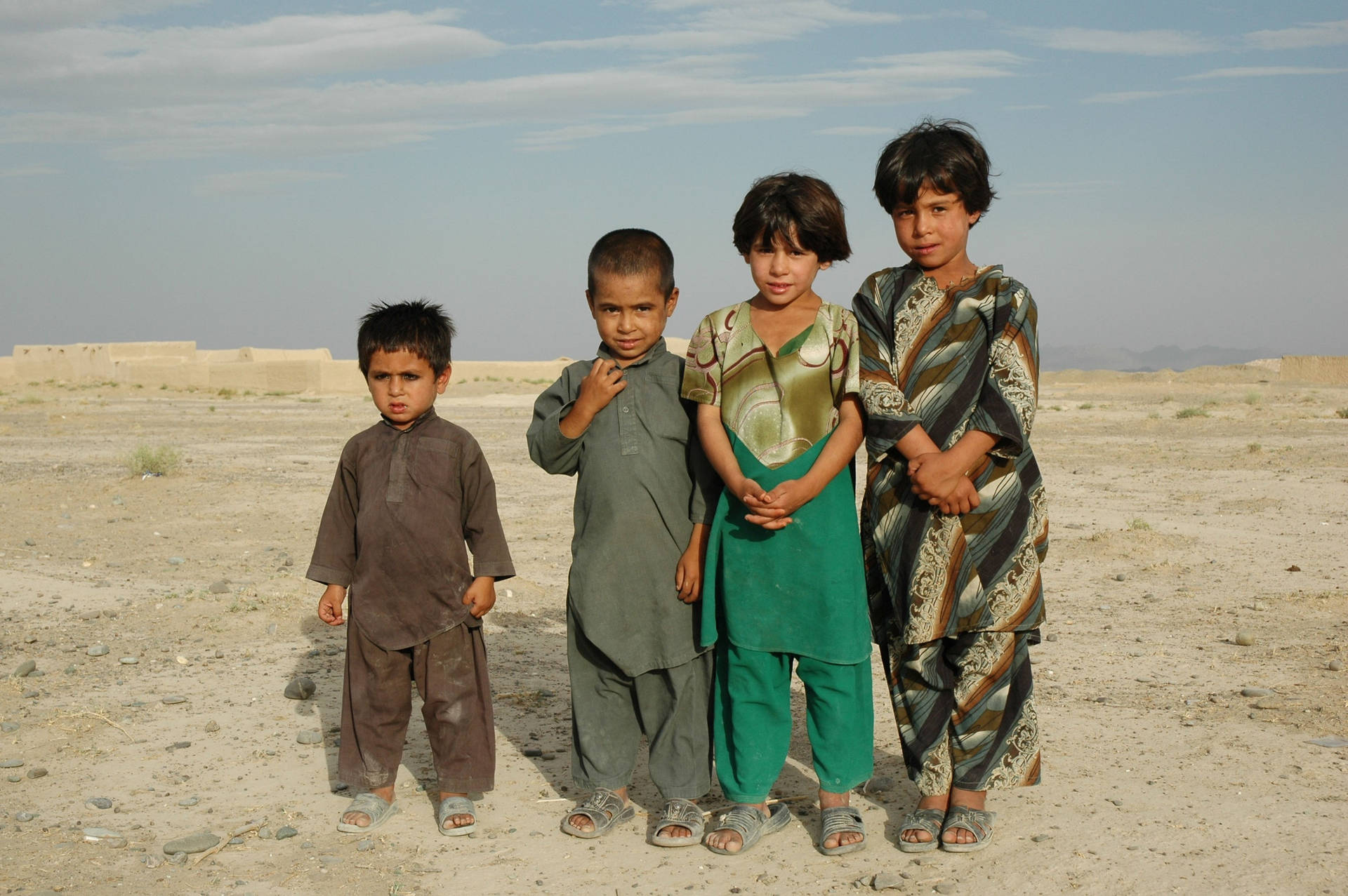 Young Boys In Traditional Attire Observing The Rural Landscapes Of Afghanistan Background