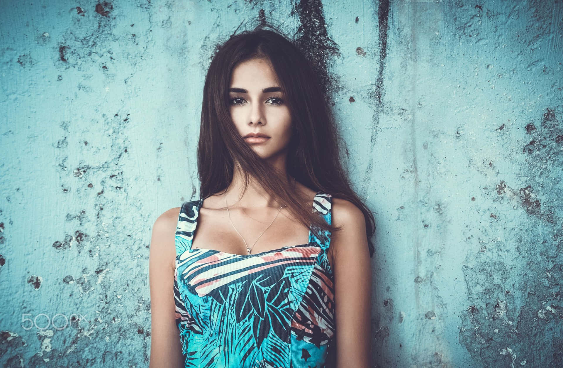 Young Female Model Showcasing Elegant Blue Dress In Outdoor Photoshoot Background