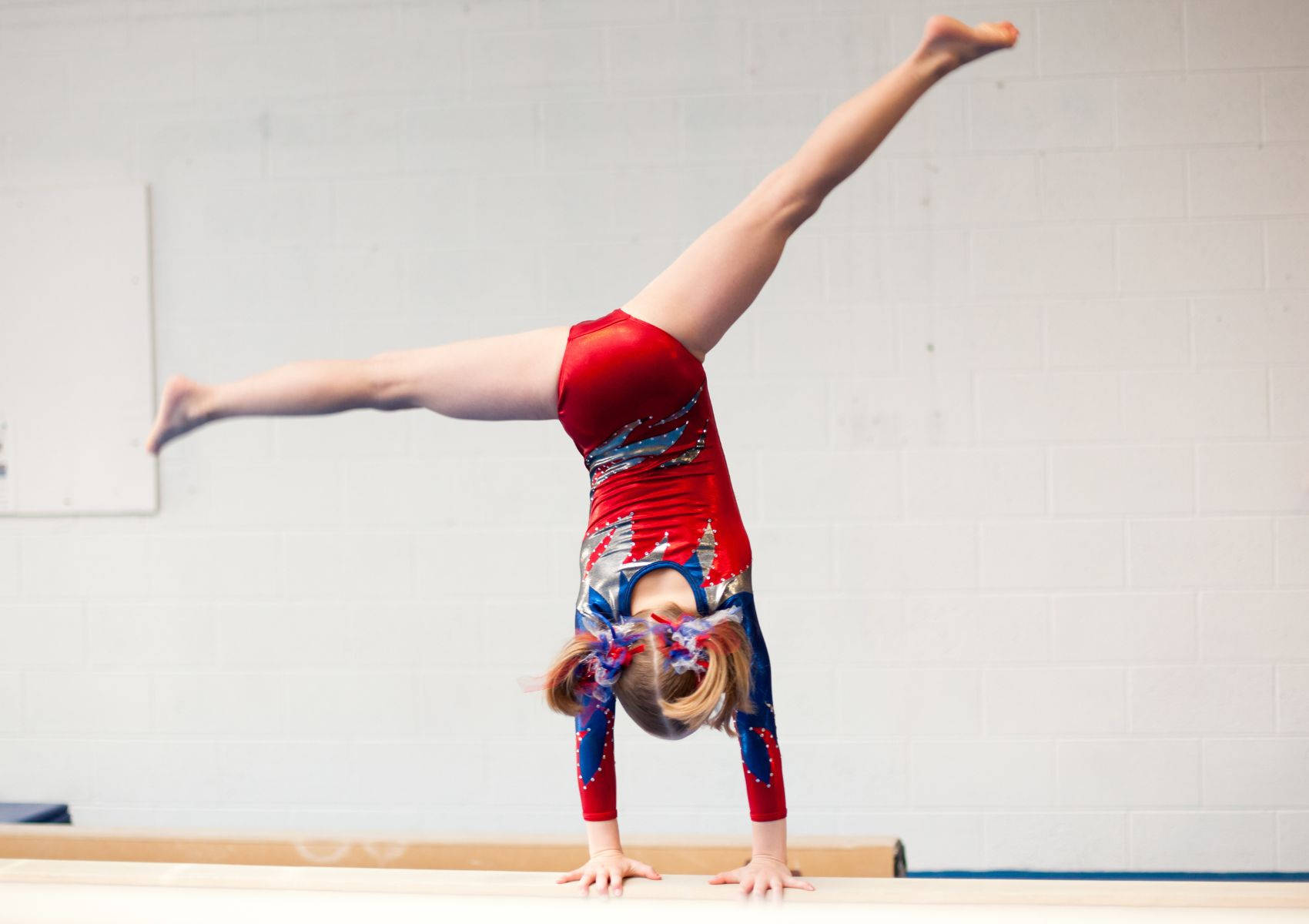 Young Gymnast Performs Cartwheel On Balance Beam Background