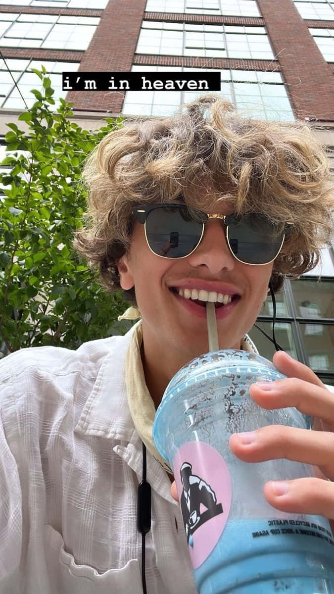 Young Man Enjoying Drink Outdoors Background