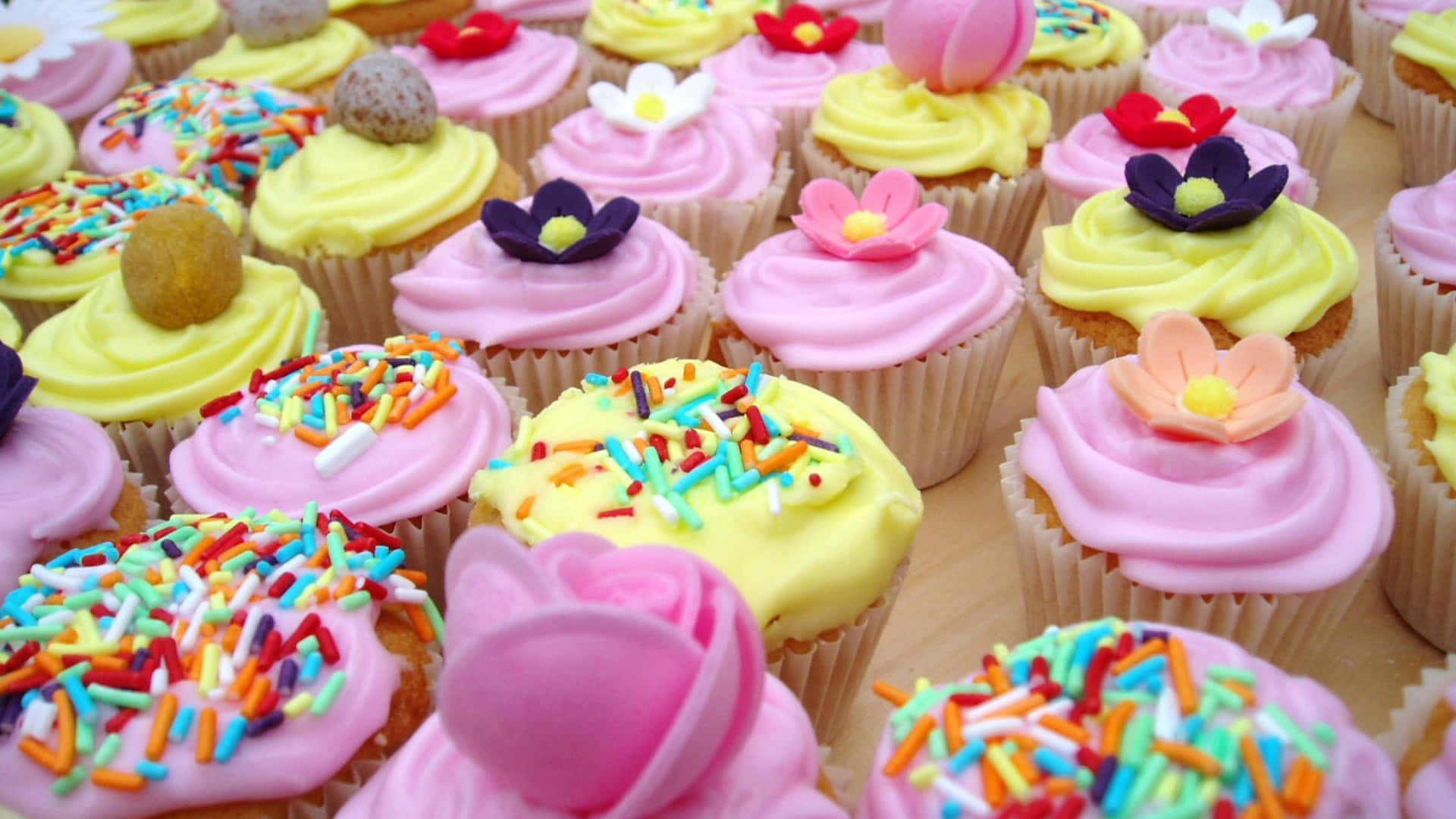 Yummy Cupcakes With Flowers And Sprinkles Background